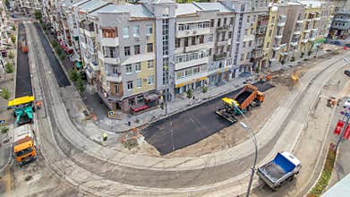 Asphalt paver, roller and truck on the road repair site during asphalting . Road construction equipment.