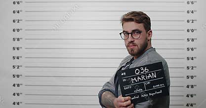 Side profile view of tough guy with beard and mustache holding sign . Male arrested person with in glasses looking to