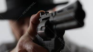 Gangster, cowboy or detective walking with a gun pointing it at the camera