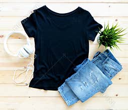 Black tshirt mockup and short jeans on brown wooden background. Template, flat lay, template