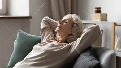 Peaceful older 60s lady resting on comfortable couch