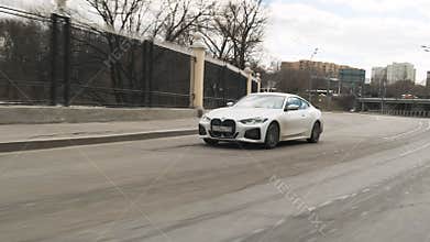 Moscow, Russia - CIRCA 2021: New model BMW 420d 4th model on the road. White dirty coupe in town. Front view footage of