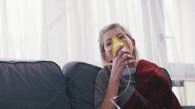 Ill elderly woman using oxygen mask at home. Treatment of allergy or lung disease.