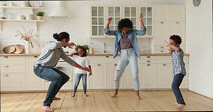 Happy active african american family dancing in kitchen.