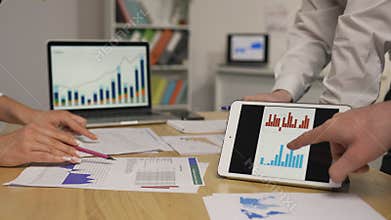 Business partners discussing economic situation of company at meeting in office. Group of men and women viewing graph