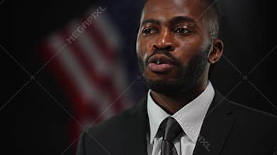 Close-up portrait of confident African American male politician diplomat answering questions at news conference. Serious