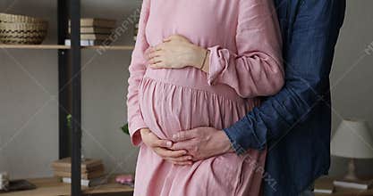 Closeup cropped view loving husband hugs from behind pregnant wife