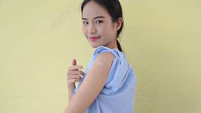 Young Asian woman showing COVID-19 vaccine bandage merrily