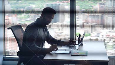 Indian investment banker working with tablet using pc laptop in office.
