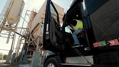 The truck driver gets into his truck to transport the cargo
