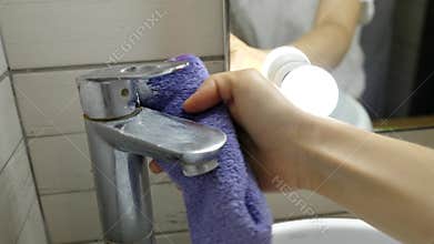 Woman is cleaning the tap in the bathroom, close-up hands