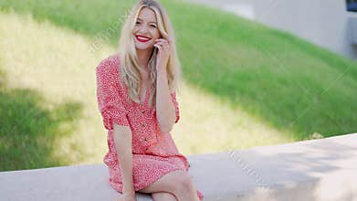 Positive young female sitting on border in park
