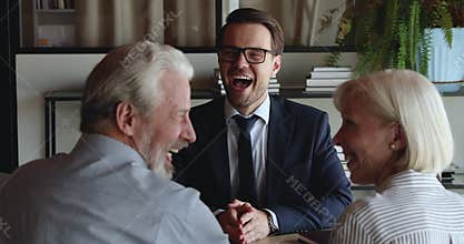 Happy older spouses receive professional consultation from insurer during meeting