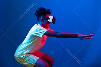 African American wearing VR exercising body weight squat neon wall. Contrivance.