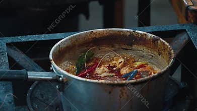 Dirty iron saucepan with boiling tom yum soup inside