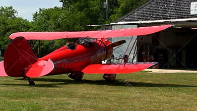 Red biplane startup on summer day
