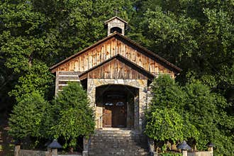 The sunlight shining and the green nature trees surrounding at an outdoor brown wooden chapel