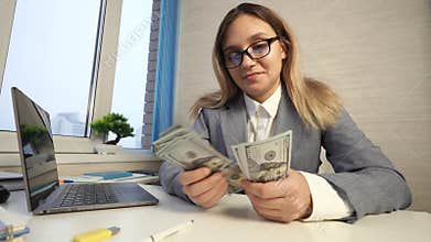 business woman counting money at office desk. Smiling girl rejoicing with good deal in workplace.