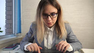 Indoor caucasian thoughtful female in glasses sitting at the table using notebook. Education and business concept