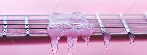 Icicledecorated guitar strings on pastel pink background