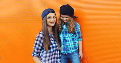 Stylish mother and child daughter together, happy mom with kid girl in casual clothing in the city
