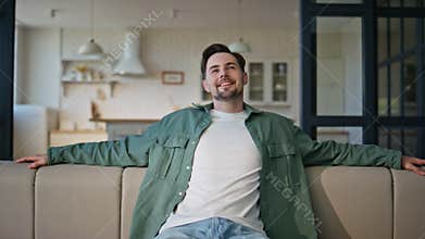 Happy man taking seat on sofa feeling comfortable home closeup. Guy work break