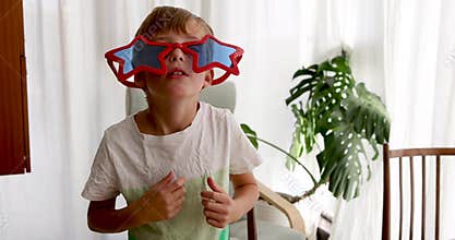 Cheerful boy with star shaped sunglasses playing and looking at sister