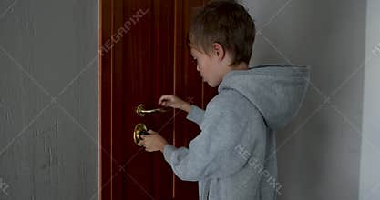 Young boy unlocking home door with key in hallway