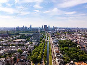 High angle view of The Hague city featuring modern buildings, green spaces, a canal and parked cars on a sunny summer