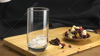 Putting ice cubes into transparent glass.