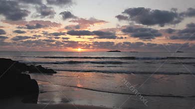 Sunrise over the sea with clouds and reflections on a tropical beach.