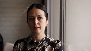 Brunette hair mother worried looking in window, waiting for husbands with kids. Angry mommy stressed staying home alone