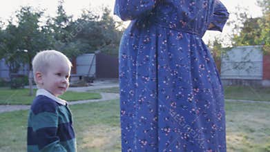 Little boy rubbing his pregnant mom's belly outdoor