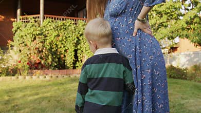 Little boy hearing his pregnant mom's belly outdoor