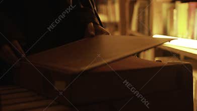 Close-up of mysterious man opening large book. Stock footage. Man opens book in dark library with flashing light. Secret