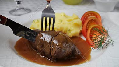Chef hand cuts with knife beef rouladen stuffed with mustard, onions, pickled cucumber and bacon
