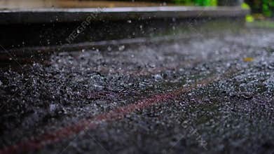 Rain drops falling on asphalt in slow motion loop during a rain storm