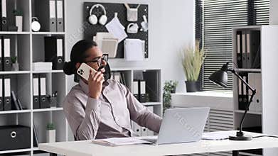 Relaxed Indian Businessman Talking On Phone In Office