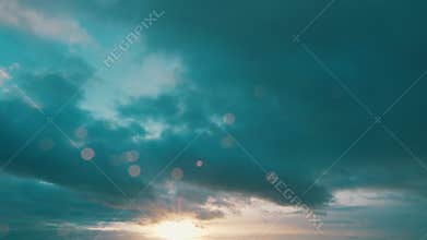 Sun below the horizon and clouds in the fiery dramatic sky. Clouds illuminated by sunbeams.