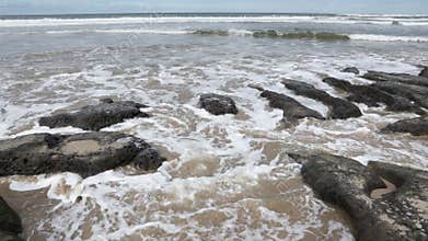 A wave of water arriving at a rocky beach and then retreating again