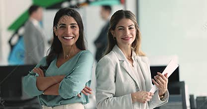 Portrait of two beautiful successful businesswomen posing at workplace