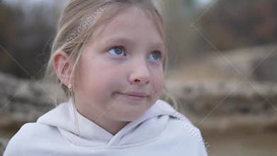 Close-up of the face of a serious little girl with a little smile