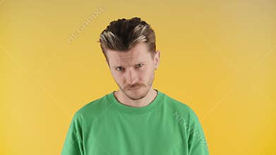 A man with stubble and a stylish hairstyle stares into the camera. A serious young man in a green t-shirt stands on a