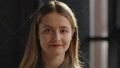 Attractive young blonde woman is looking at the camera and smiling. A young long-haired woman poses for the camera and