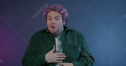 Slow motion portrait of surprised young man showing thumbs-up saying wow expressing amazement on purple background