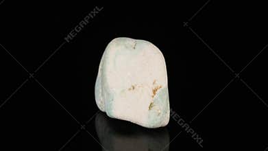 Polished mineral stone zoisite rotates in a circle on a black background