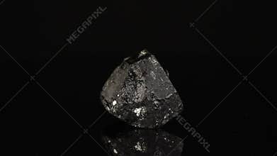 Polished mineral stone Schorl rotates in a circle on a black background