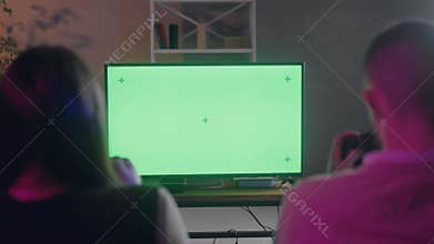 Rear shot of couple friends playing console game tournament. Two players fast clicking their remote controllers during