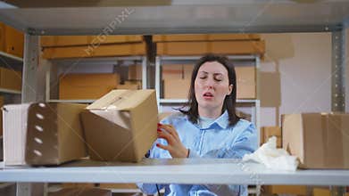 A sick young woman at work in a box warehouse sneezing allergies