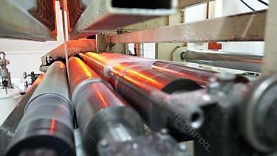 Thin paper sheet rolled through press machine at plant